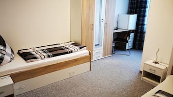A bedroom with a bed, a wardrobe, a desk, and a chair.