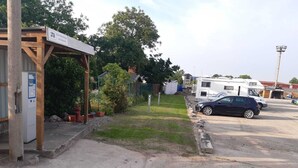 Un área de estacionamiento con estructura cubierta, una gasolinera y una fila de vehículos recreativos.