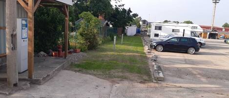 A parking area with a covered structure, a gas pump, and a row of RVs.