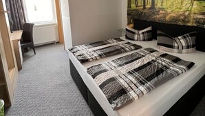 Una habitación de hotel moderna con una cama grande, un escritorio y un mural temático de bosque.