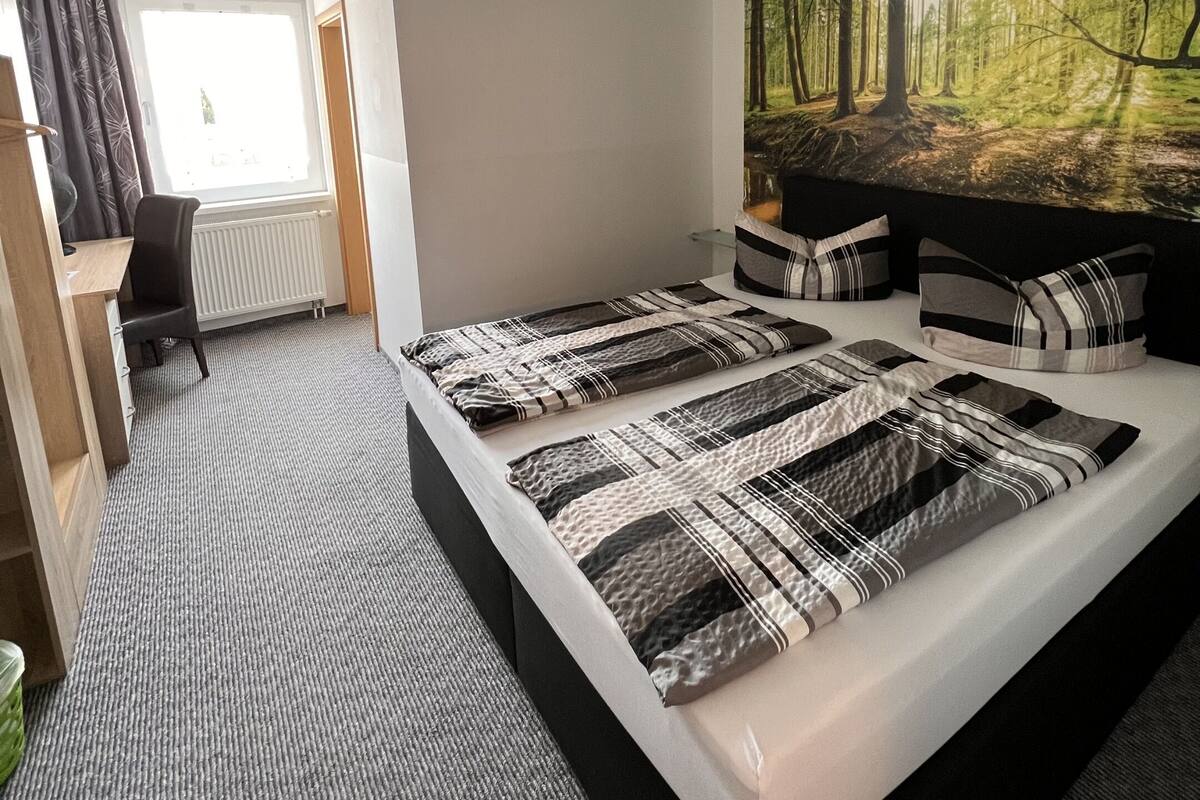 Una habitación de hotel moderna con una cama grande, un escritorio y un mural temático de bosque.