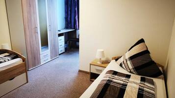 A bedroom with a bed, a wardrobe, a desk, and a chair.
