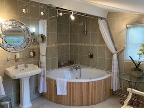 A bathroom with a freestanding bathtub, a pedestal sink, and a shower area. - Old White Hart (Oakham)