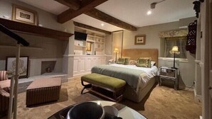 A bedroom with a large bed, a bedside table, a lamp, a chair, and a small table with a pitcher. - Old White Hart (Oakham)