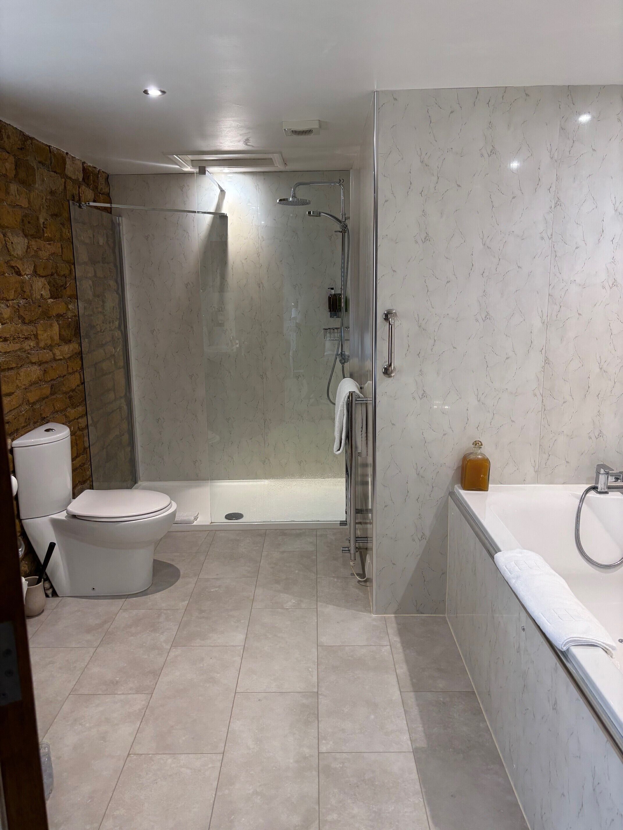 Un bagno moderno con cabina doccia in vetro, un water e una vasca da bagno.