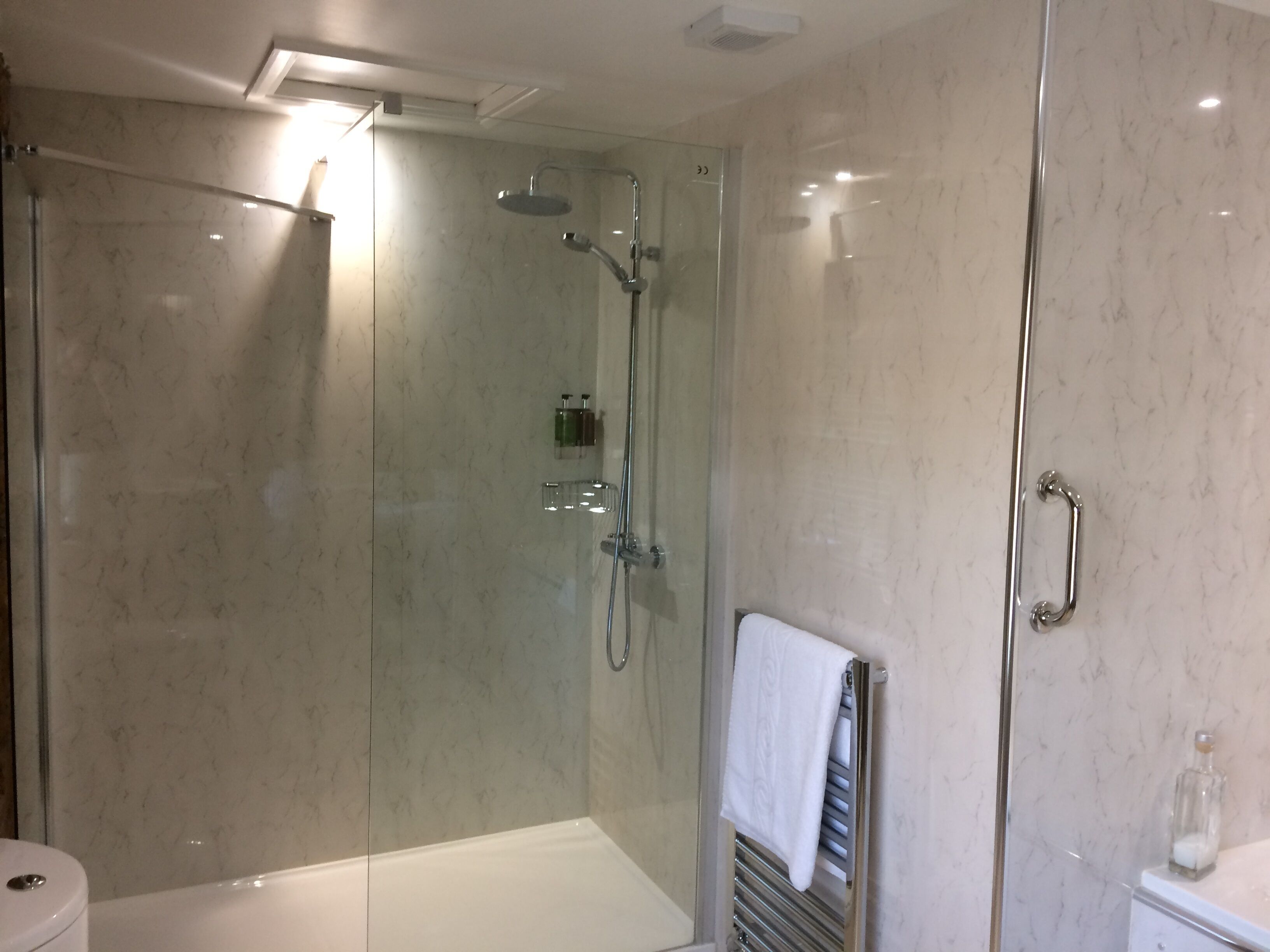A modern bathroom with a glass-enclosed shower, a white bathtub, and a glass-enclosed toilet.