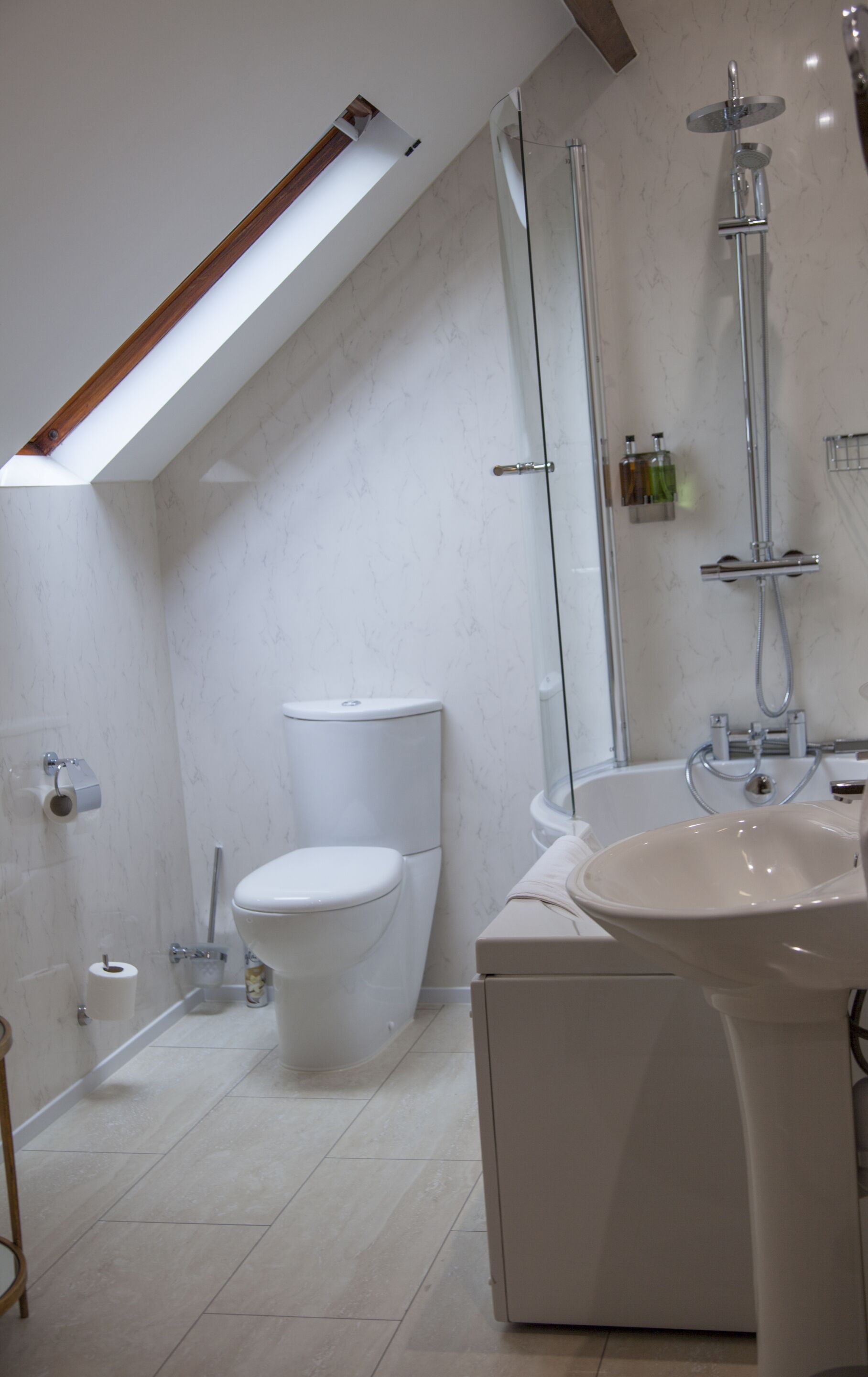 A modern bathroom with a skylight, a toilet, a shower, and a sink.