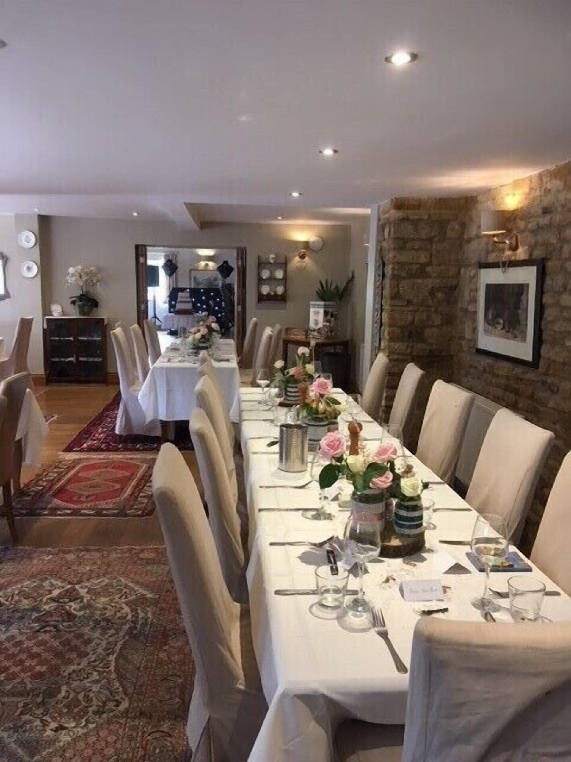 A long dining table set with white tablecloths, chairs, and floral centerpieces.
