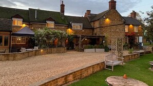 A stone building with a gravel patio and outdoor seating. - Old White Hart (Oakham)