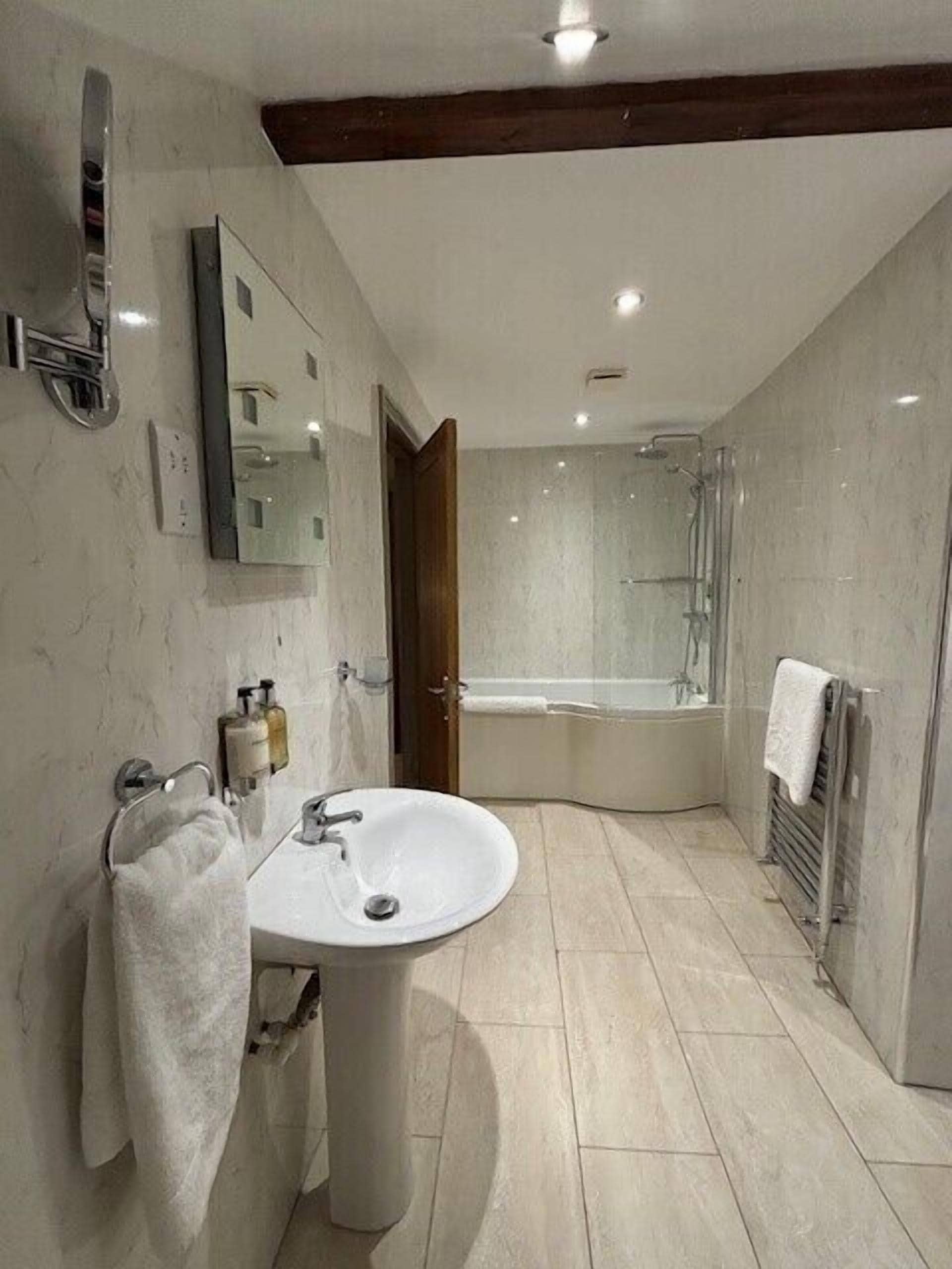A modern bathroom with a white sink, mirror, and a shower area.