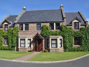 A two-story house with a brick facade, a dark roof, and a front entrance with a door and windows. - Plawsworth Aparthotel (Chester-le-Street)