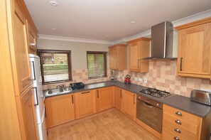 A kitchen with wooden cabinets, a stainless steel range, and a gas stove. - Plawsworth Aparthotel (Chester-le-Street)