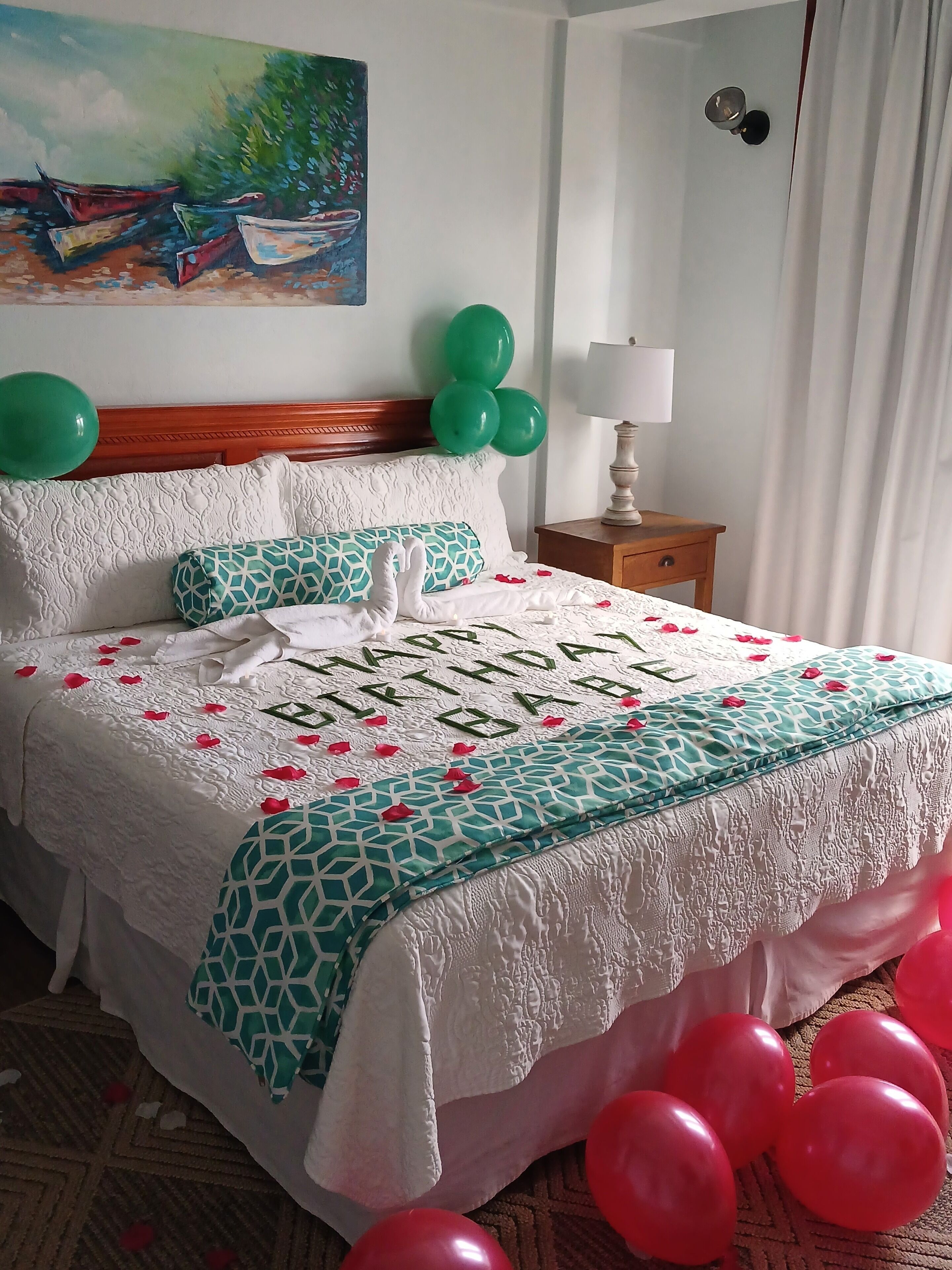A bed with a white and teal patterned bedspread, a decorative swan, and the text "Happy Birthday" on the bed.