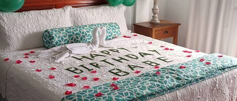 Ein Bett mit einer Bettdecke in Weiß und Türkis mit einem dekorativen Schwan und der Aufschrift 'Happy Birthday'.