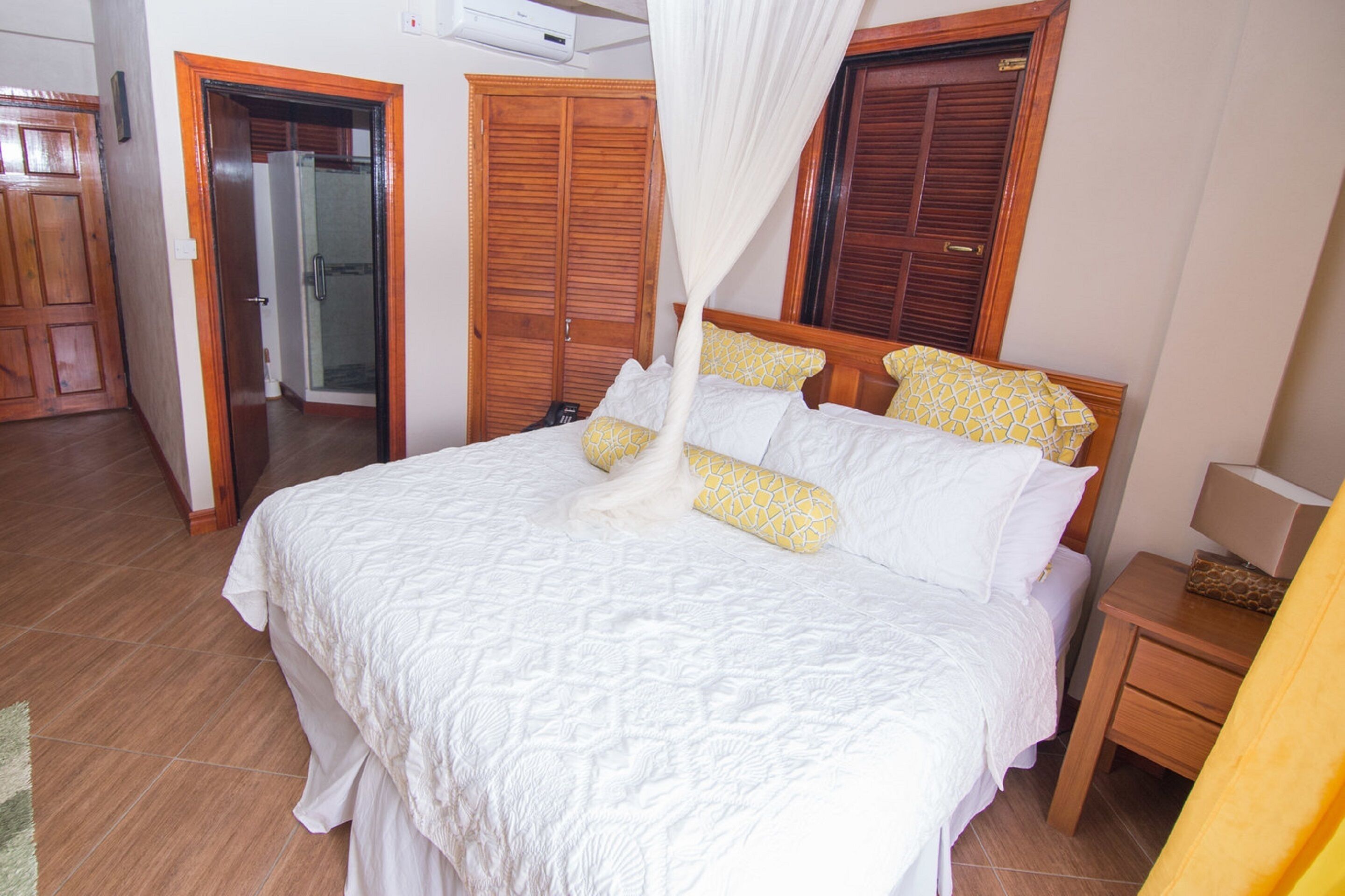 Un dormitorio con una cama grande, un armario de madera y una mesita de noche.