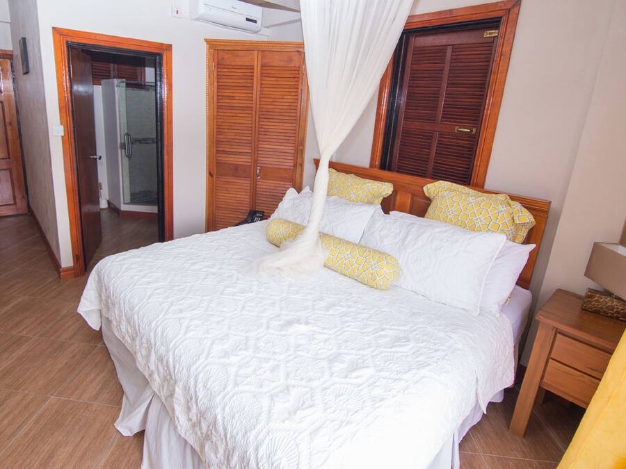 A bedroom with a large bed, wooden wardrobe, and a bedside table.