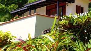 A small building with a red door and a white fence in front. - Samfi Gardens (Soufrière)