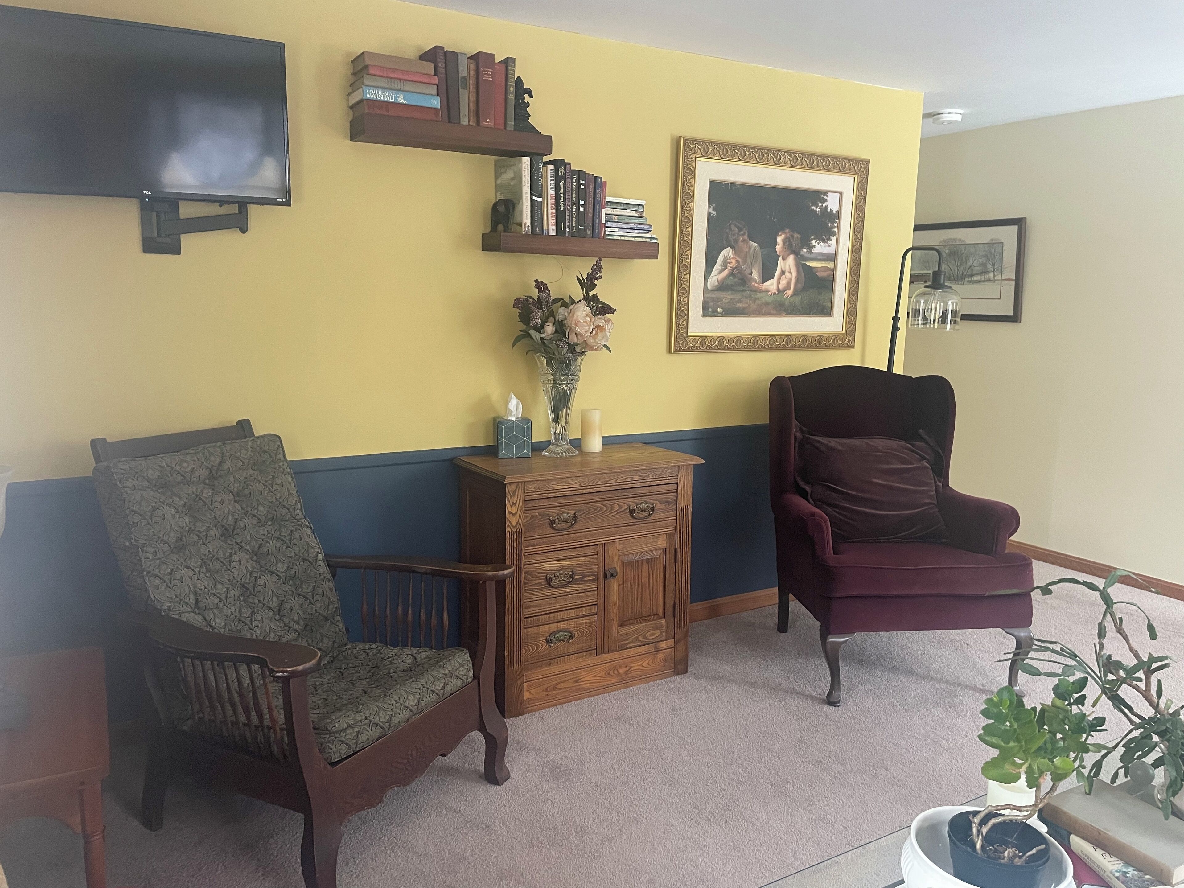Una sala de estar con dos sillones, un aparador de madera, un televisor y un cuadro en la pared.