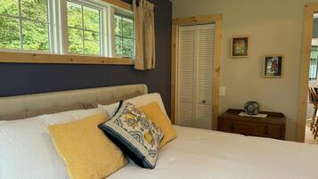 Un dormitorio con cama, ventana, armario y mesita de noche.