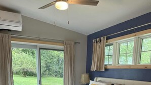 Un dormitorio con una cama grande, un ventilador de techo y vistas al exterior.