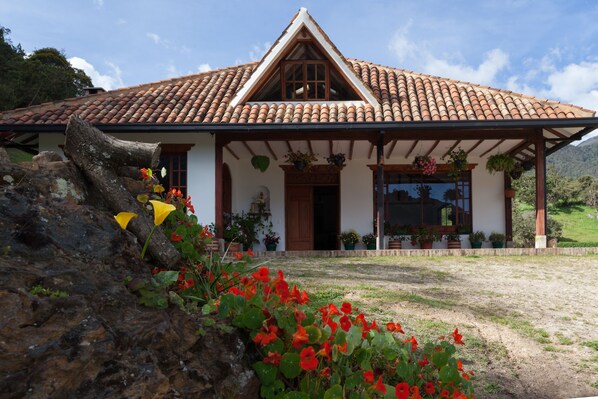 A traditional house with a tiled roof, a wooden porch, and potted plants.