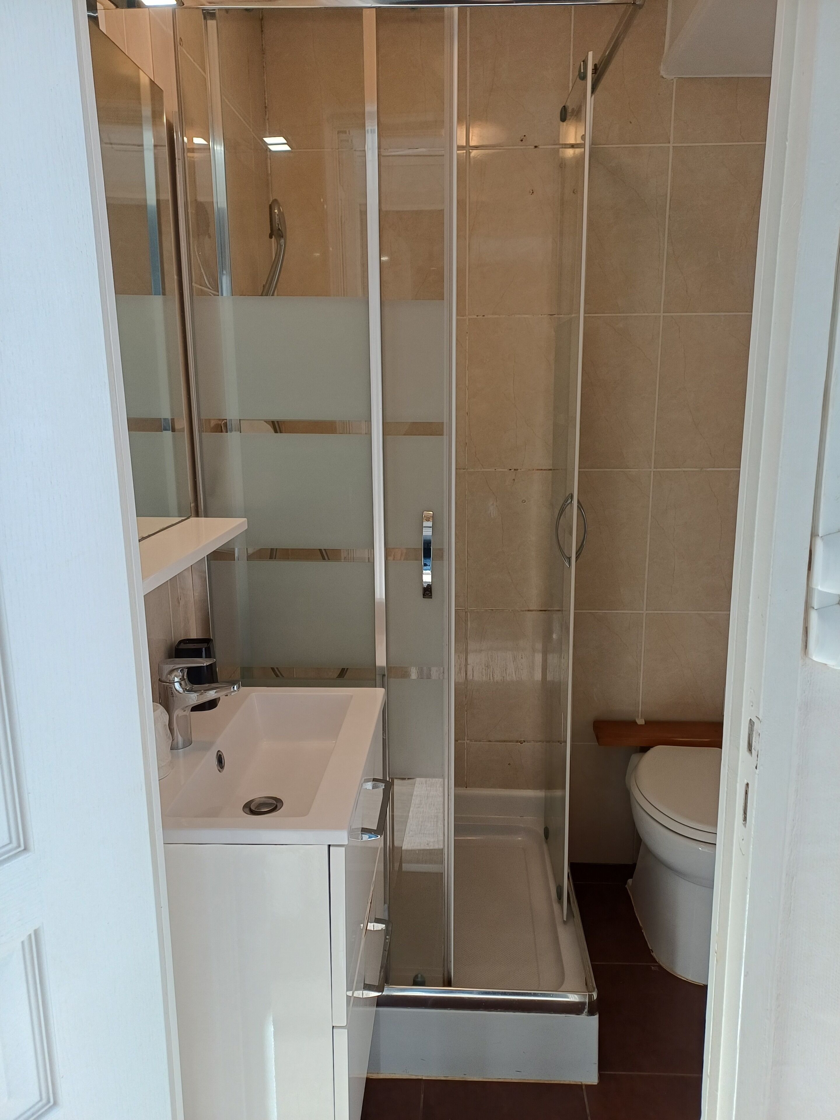 A bathroom with a glass-enclosed shower, a white sink, and a toilet.
