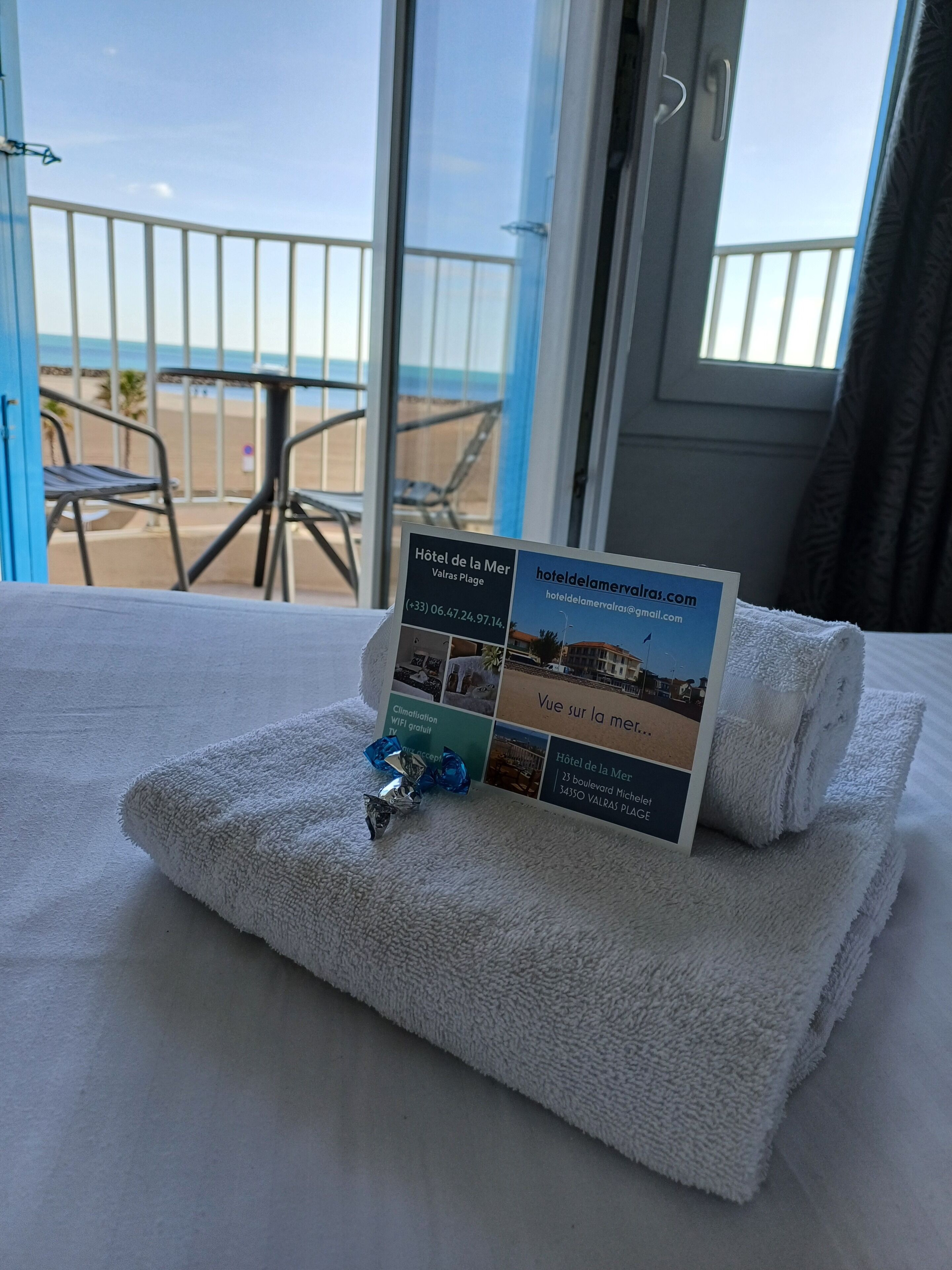 Habitación de hotel con vista al mar, un folleto sobre la cama y una toalla.