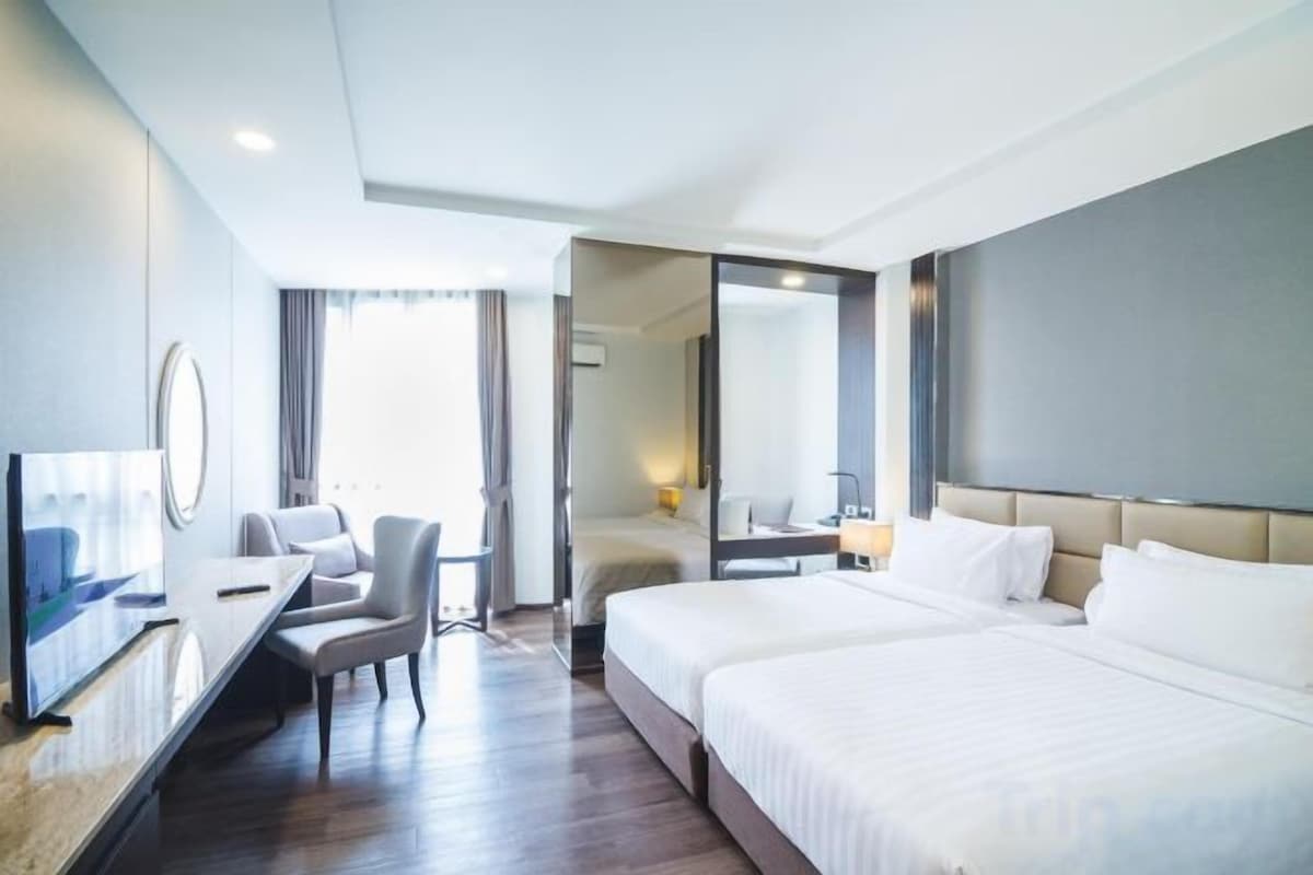 A hotel room with a bed, a desk, a chair, and a television.