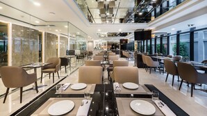 A modern dining area with glass walls, multiple dining tables, and chairs. - SureStay Plus Hotel by Best Western Sukhumvit 2 (Bangkok)