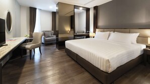 A modern hotel room with a large bed, a desk with a chair, a TV, and a mirror. - SureStay Plus Hotel by Best Western Sukhumvit 2 (Bangkok)