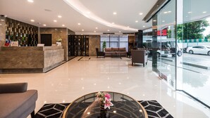 A modern hotel lobby with a reception desk, seating area, and large windows offering a view of the street. - SureStay Plus Hotel by Best Western Sukhumvit 2 (Bangkok)