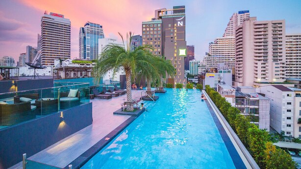 A rooftop pool with lounge chairs and palm trees, surrounded by high-rise buildings. - SureStay Plus Hotel by Best Western Sukhumvit 2 (Bangkok)