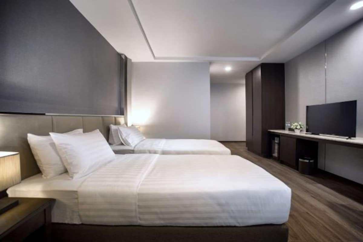 Una habitación de hotel moderna con dos camas, un televisor de pantalla plana y un diseño minimalista.