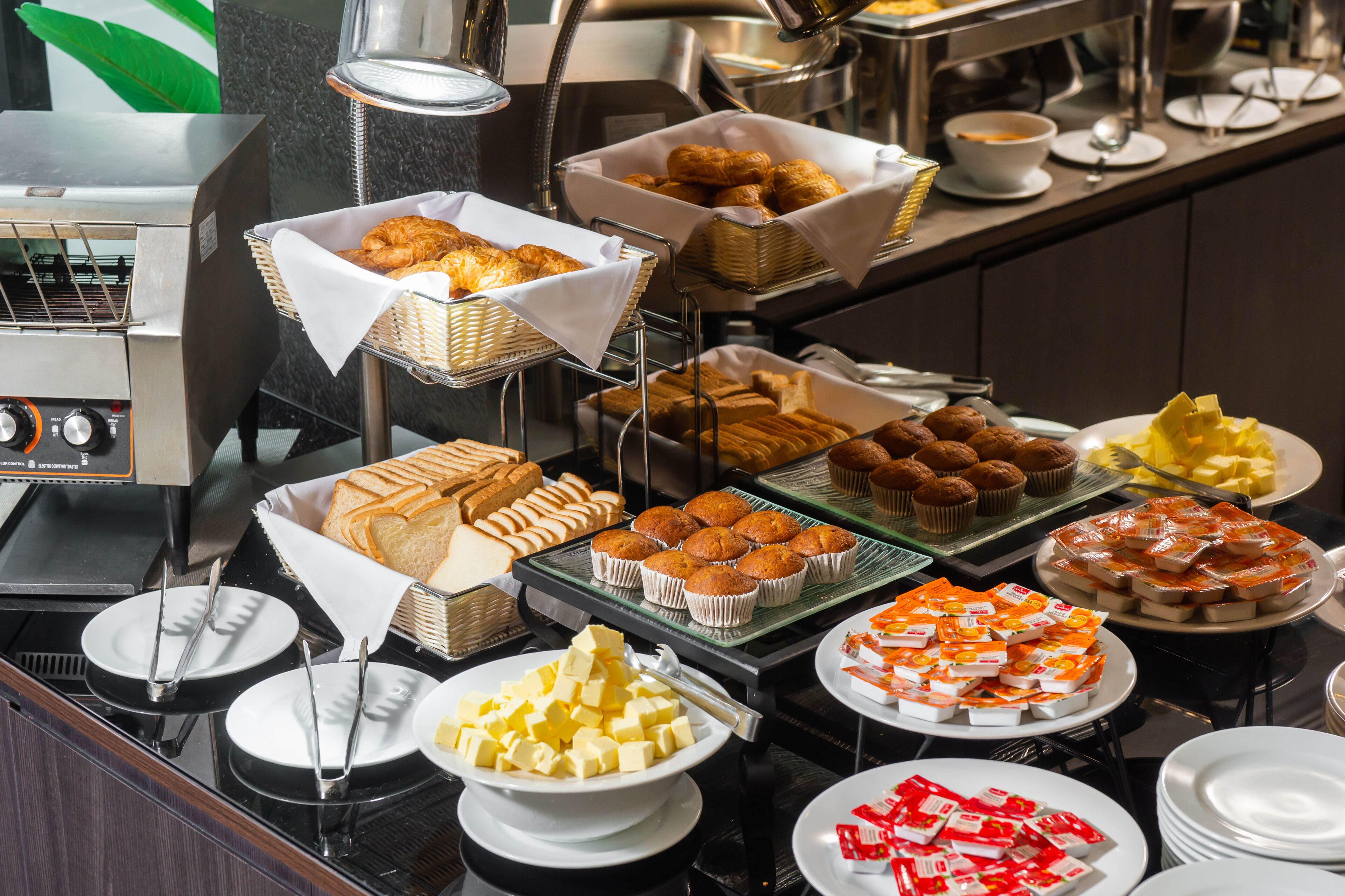 Un bufé con diversos alimentos, incluyendo pasteles, muffins y postres.