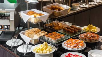 Un bufé con diversos alimentos, incluyendo pasteles, muffins y postres.