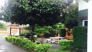 A garden area with a white picnic table, a statue, and a building entrance. - Bai Pai Resort (Khlung)