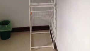 A white metal shelf unit with a wire basket and a hook. - Bai Pai Resort (Khlung)