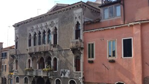A historic building with ornate balconies and arched windows, adjacent to a canal. - A quiet corner in the "True Venice" (venezia)