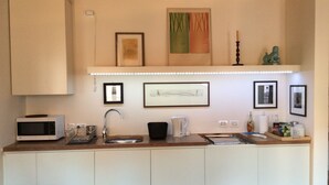 A compact kitchen with a microwave, sink, and various kitchen items. There are framed pictures on the wall and a decorative item above the sink. - A quiet corner in the "True Venice" (venezia)