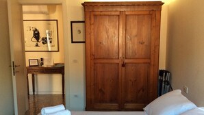 A bedroom with a bed, a wooden wardrobe, a desk with a chair, and a framed picture on the wall. - A quiet corner in the "True Venice" (venezia)