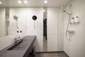 A modern bathroom with a large mirror, a sink, a shower, and a toilet. - Scandic Lillestrøm (Lillestrom)