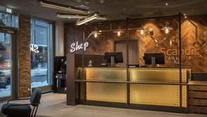Un comptoir d’accueil moderne avec une enseigne « Shop », un mur en bois avec un motif en chevrons et le logo « Scandic ».