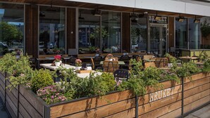 Un espace extérieur aménagé avec des tables et des chaises en bois, entouré d’un jardin en bois où sont plantées des fleurs.