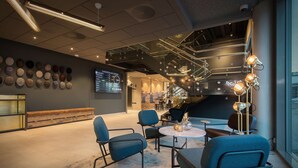 Un espace de détente moderne comprenant un coin salon, un écran numérique et un escalier.