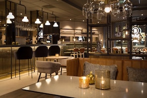 A restaurant interior with a bar area, seating with cushions, and hanging light fixtures. - Scandic Lillestrøm (Lillestrom)