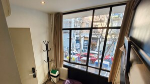 A room with a large window, a radiator, a coat rack, a purple bean bag, and a door labeled "05". - Free Hostels Barcelona (Barcelona)