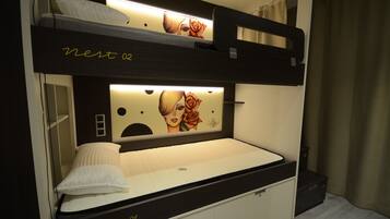 A bunk bed with a headboard featuring a graphic design and a bedside table.