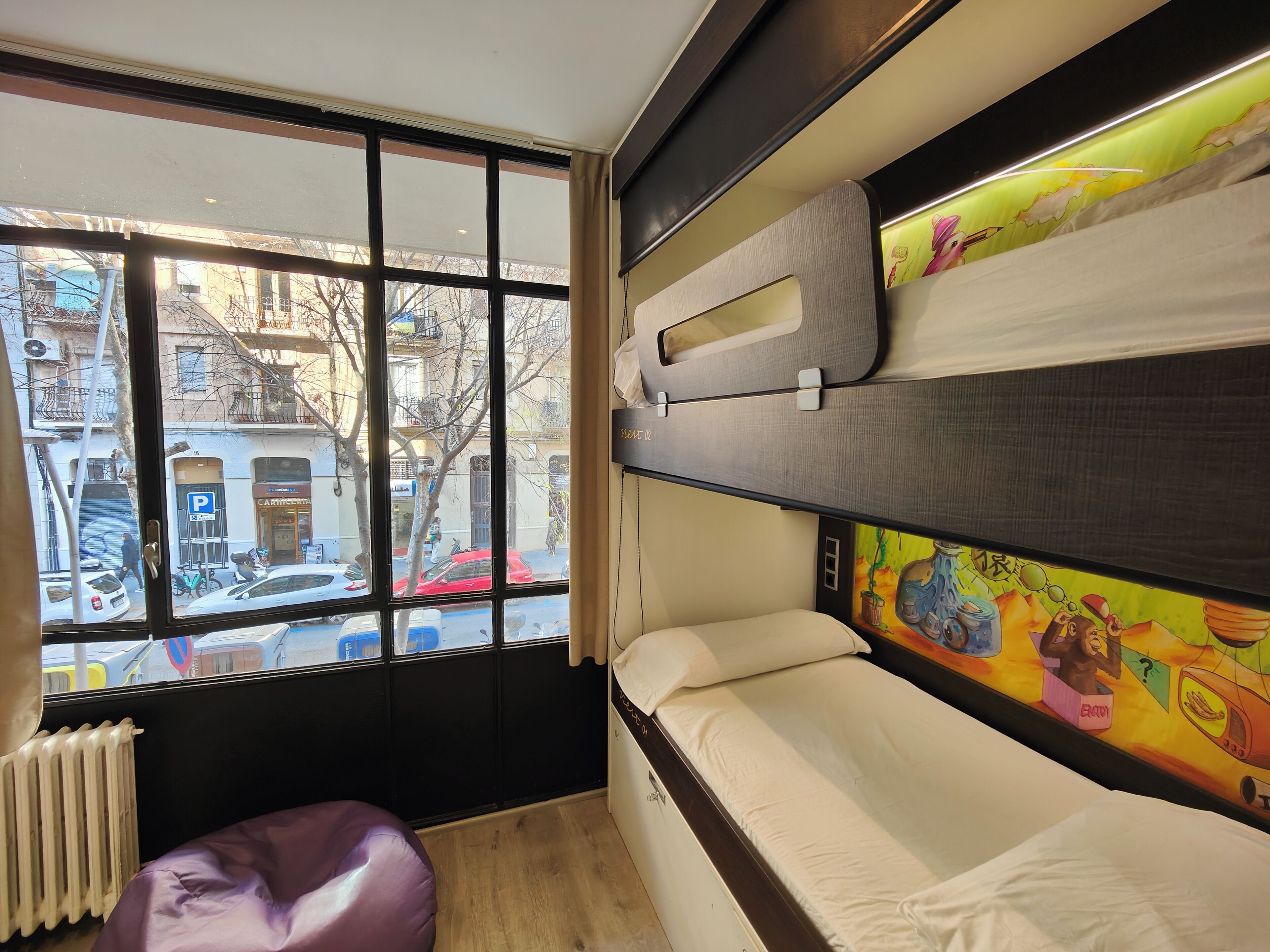 Une chambre avec un lit superposé, une fenêtre donnant sur la rue et un radiateur.