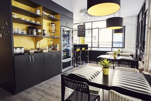 Una cocina moderna con armarios oscuros, una isla central y una zona de comedor con sillas y mesas a rayas.