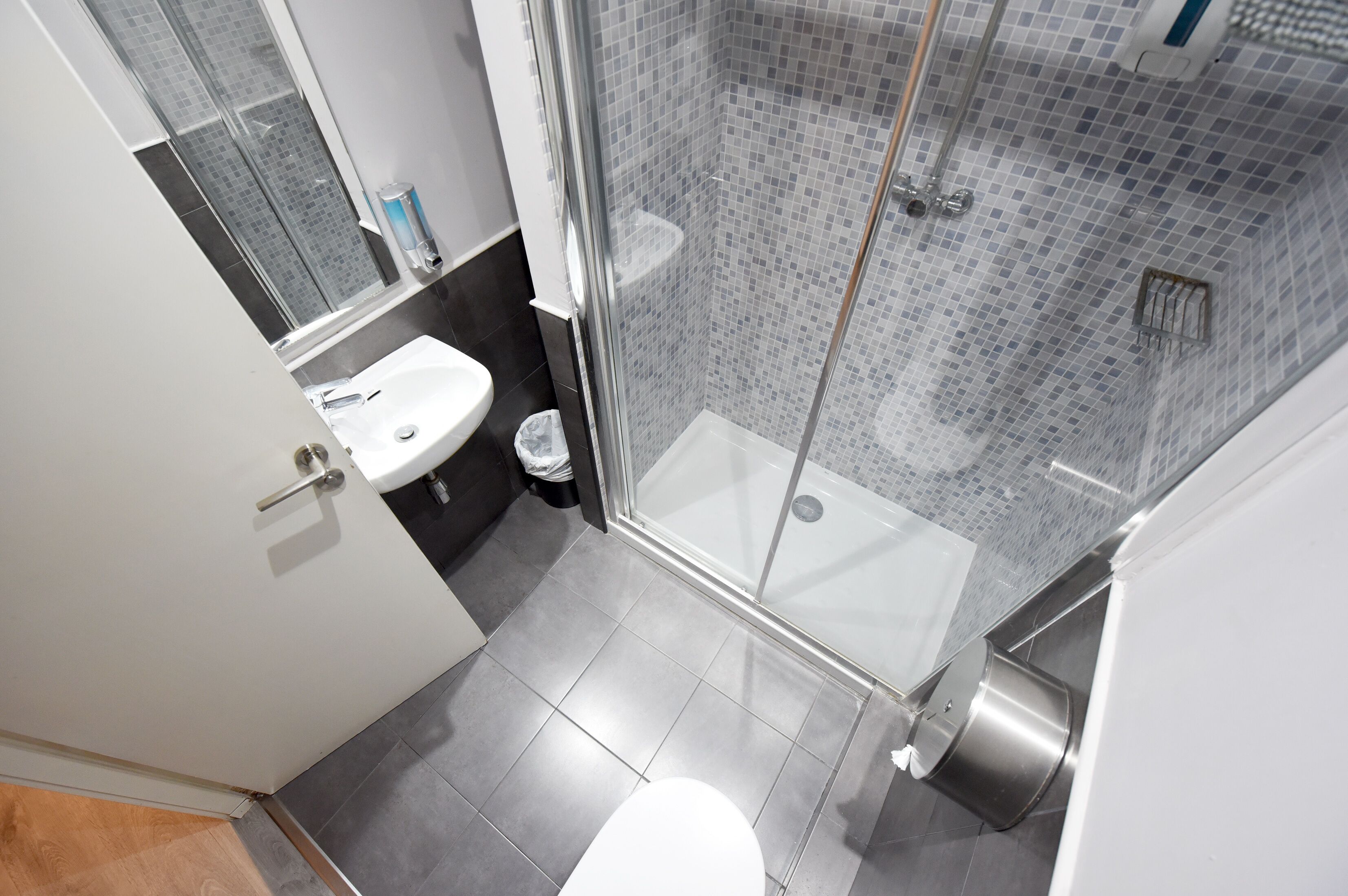 Un baño moderno con ducha acristalada, lavamanos blanco y retrete.
